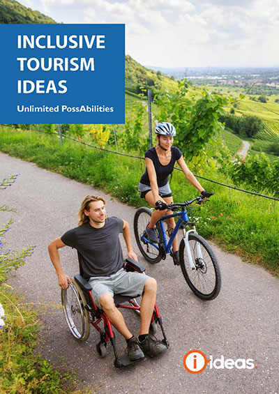 Inclusive Tourism IDEAS: Unlimited Possibilities. Book Front Cover. Image of man in wheelchair and woman on bike rolling down a roadway with a vibrant green valley in the background. 