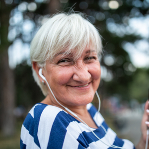 Image of elderly woman listening to a podcast through her earphones.