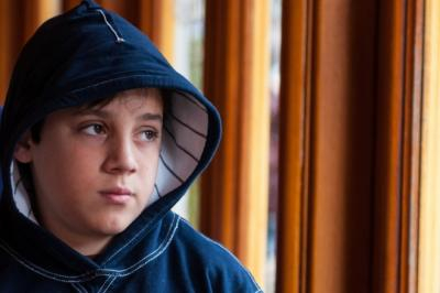 Image of a young boy with a hoodie looking thoughtful