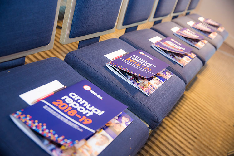 Row of blue chairs with copies of the IDEAS annual report 2018-19 placed on each seat.