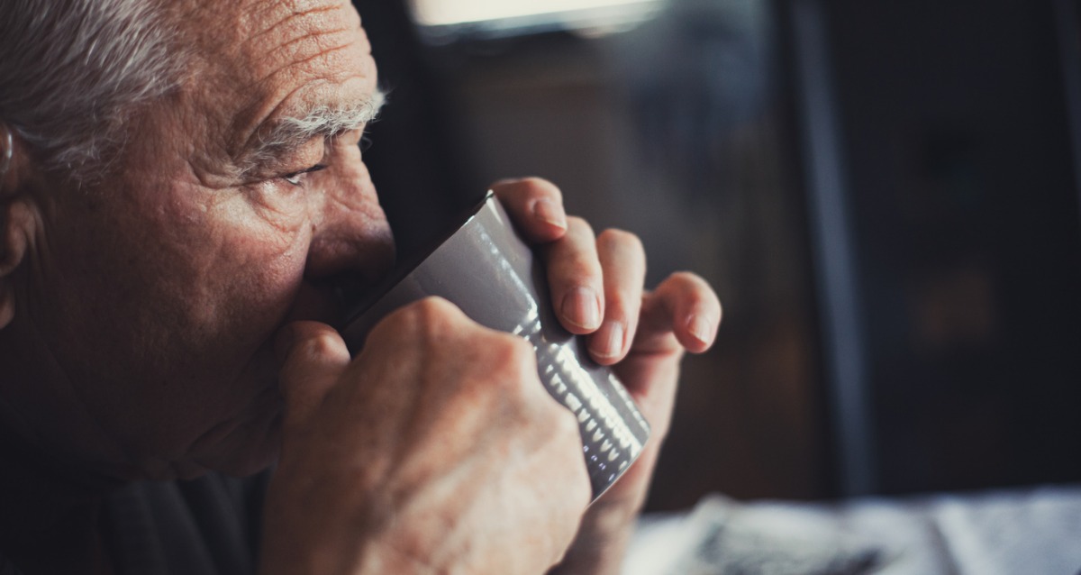 An elderly man drinking coffee