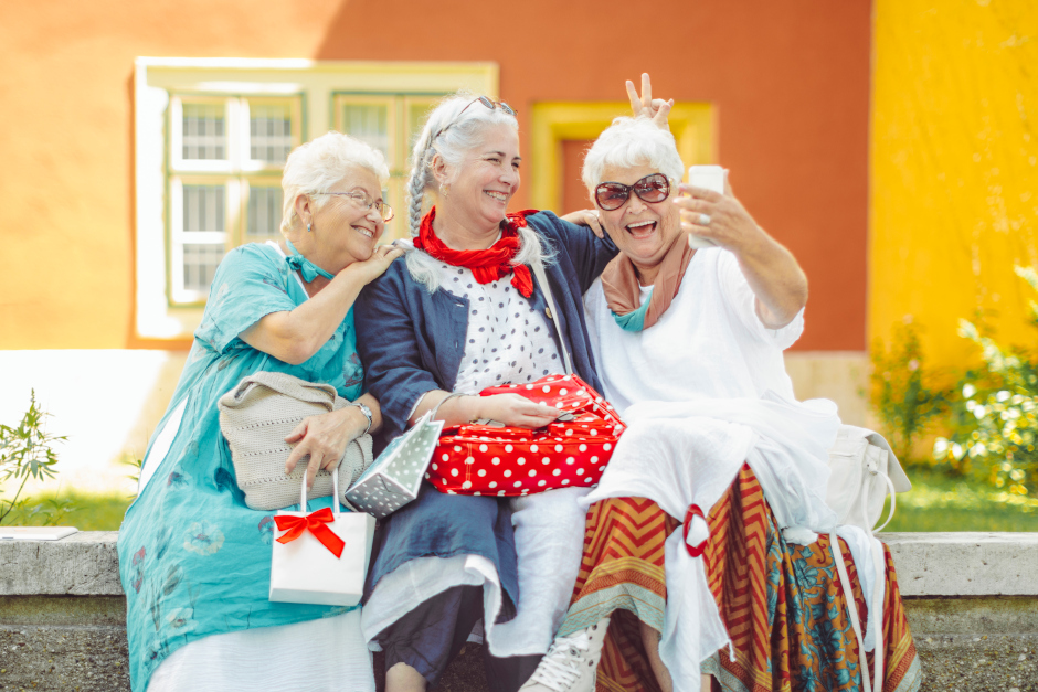 Image of three senior ladies. One is holding a phone adn they are all smiling for a selfie photo