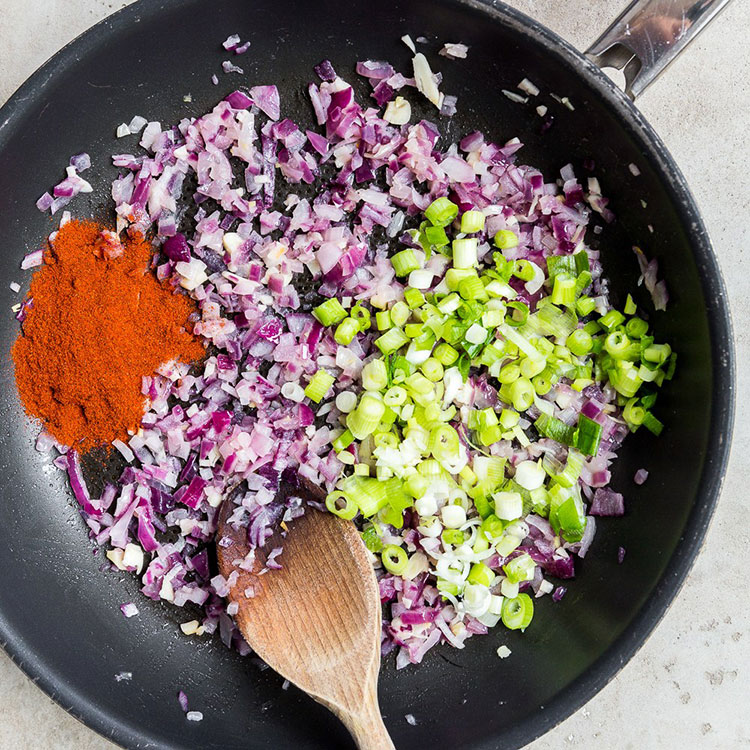 diced red onion, spring onions and paprika in a non-stick pan