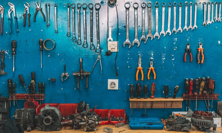 Image of organised tools hanging on a blue wall inside a garage or shed.