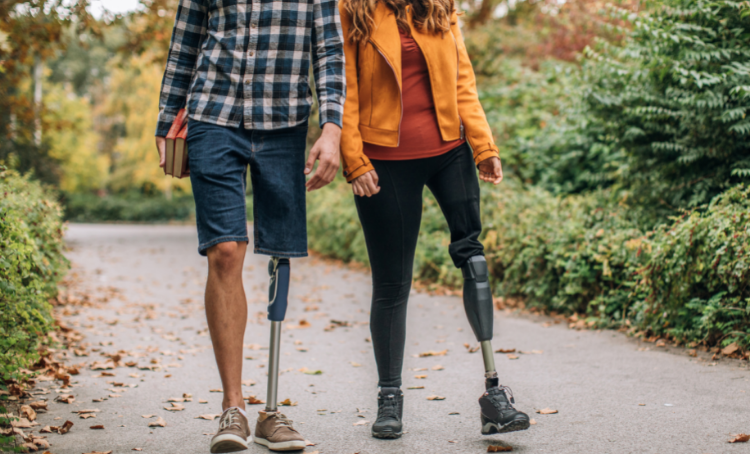 A man a woman, both with a prosthetic leg, walk together.