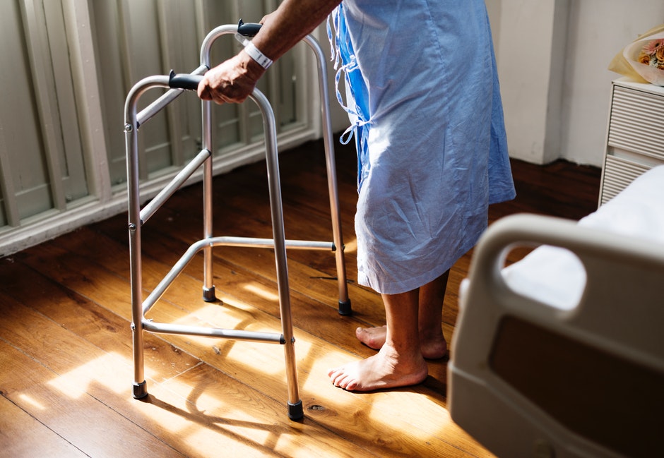 person in hospital gown using a walking frame