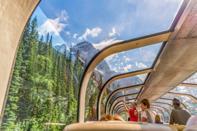 An image of the Canadian Rocky Mountains viewed from inside a train with a glass roof.
