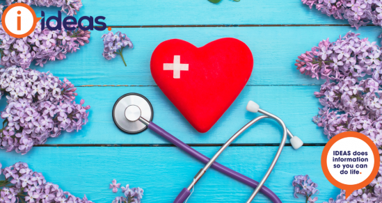  Red heart with bandaid in a cross shape, sit on a blue background. It is surrounded by lilac blooms, and a stethoscope.