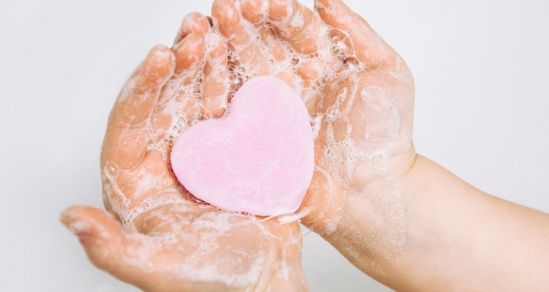 A childs hands holding heart shaped soap.