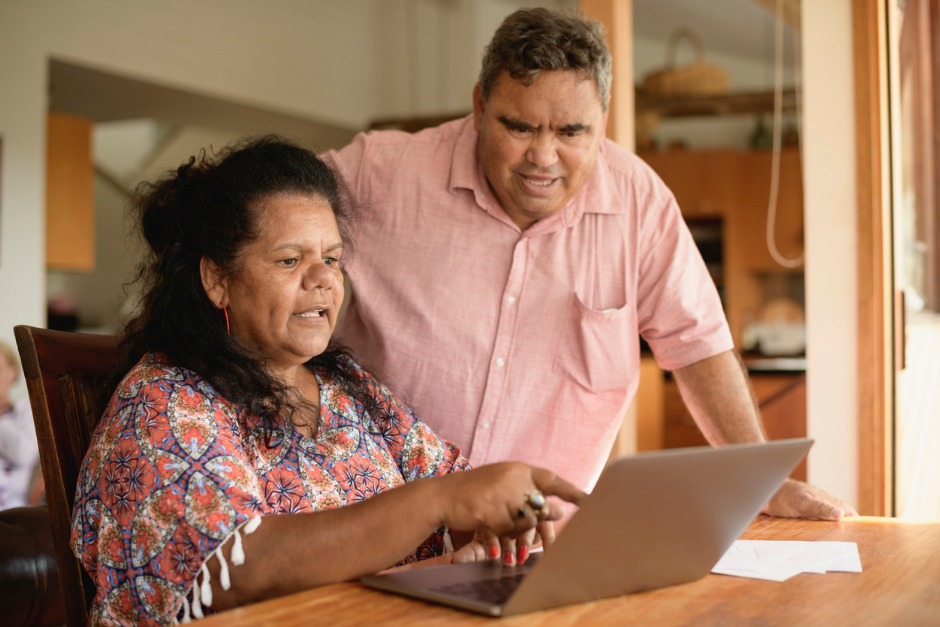 Image of elderly couple looking at a laptop computer inside their home.