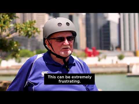 Man sitting in wheelchair with a helmet on with city background speaking