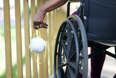 wheelchair user holding a surgical mask