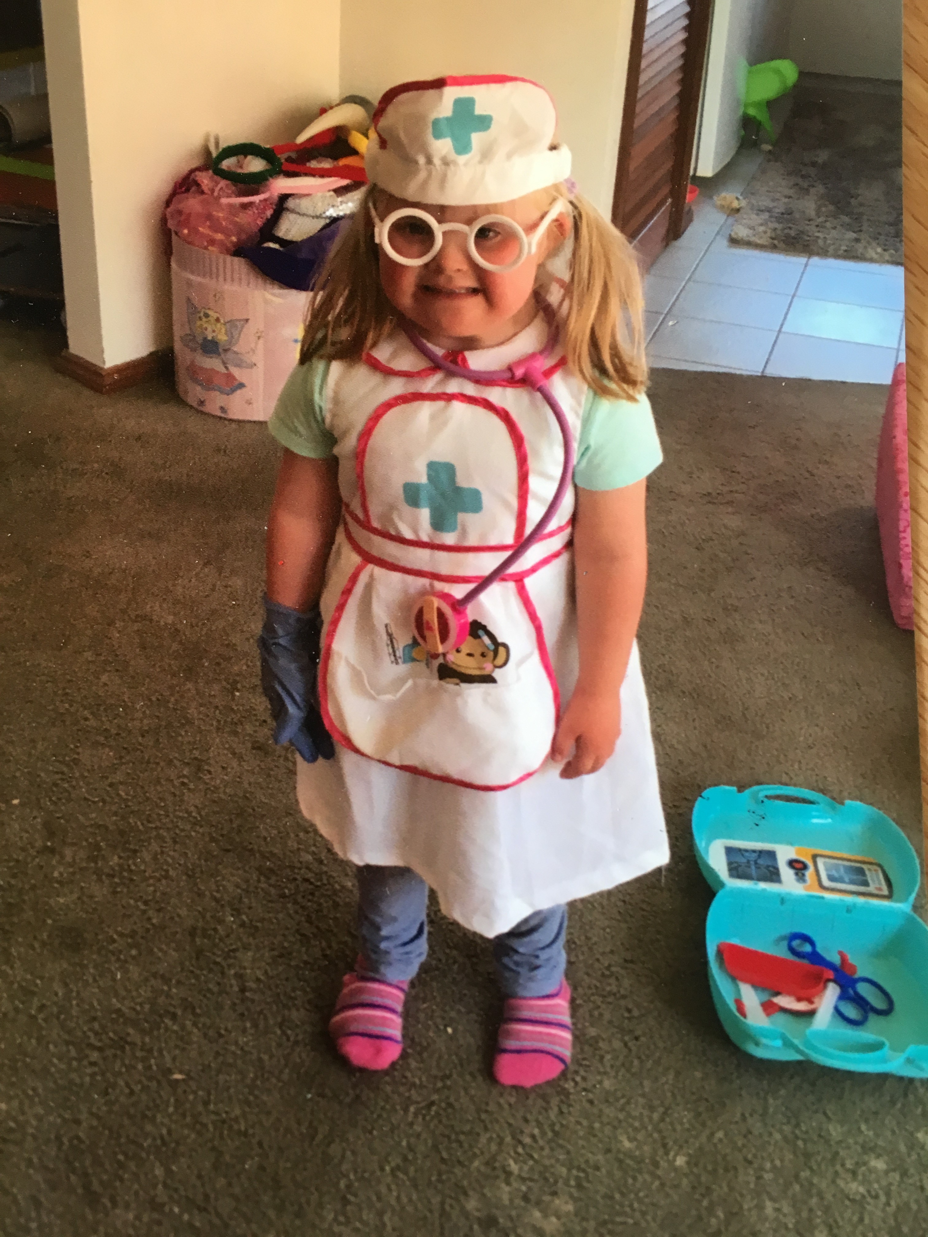 A small child is dressed as a nurse in a uniform with brightly coloured accessories