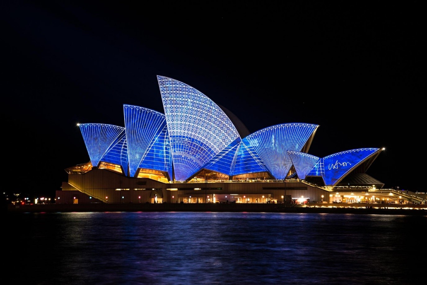 A panoramic view of Sydney Opera House lit up in patterned blue lights