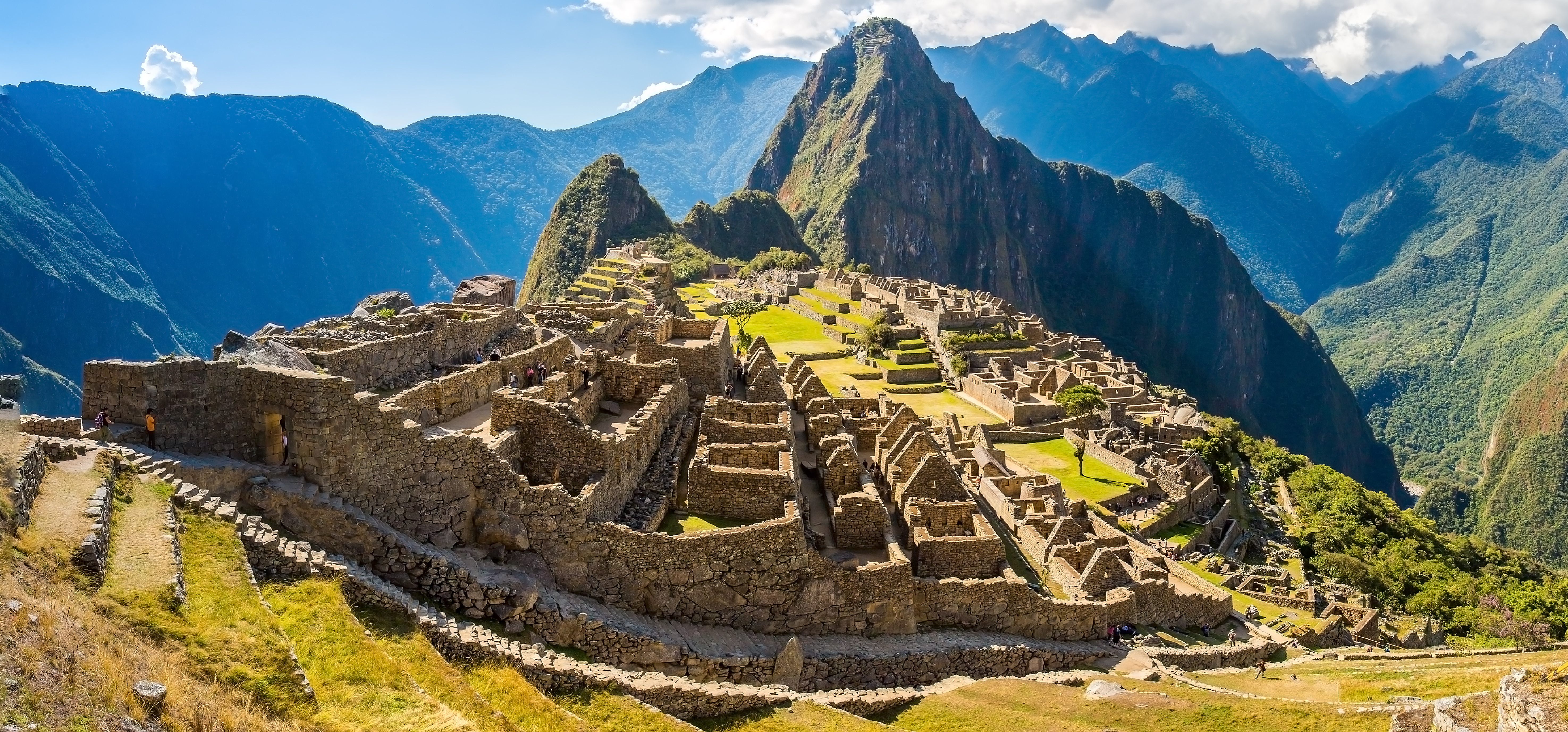 Image shows historic city of Machu Picchu with terraced city in foreground and mountain ranges in background