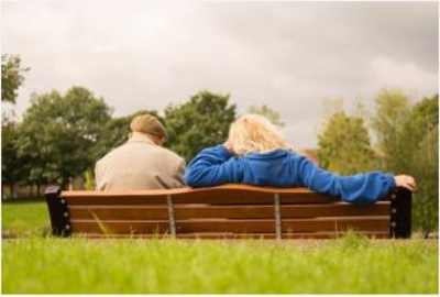 Two people sitting on a park bench, view from behind
